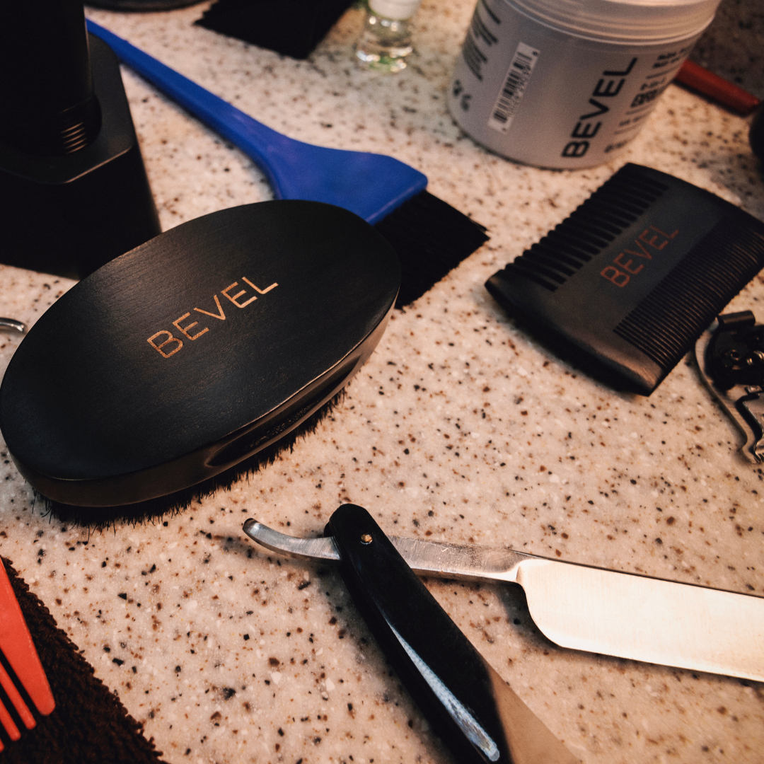 Bevel grooming tools on a speckled countertop with a razor blade.