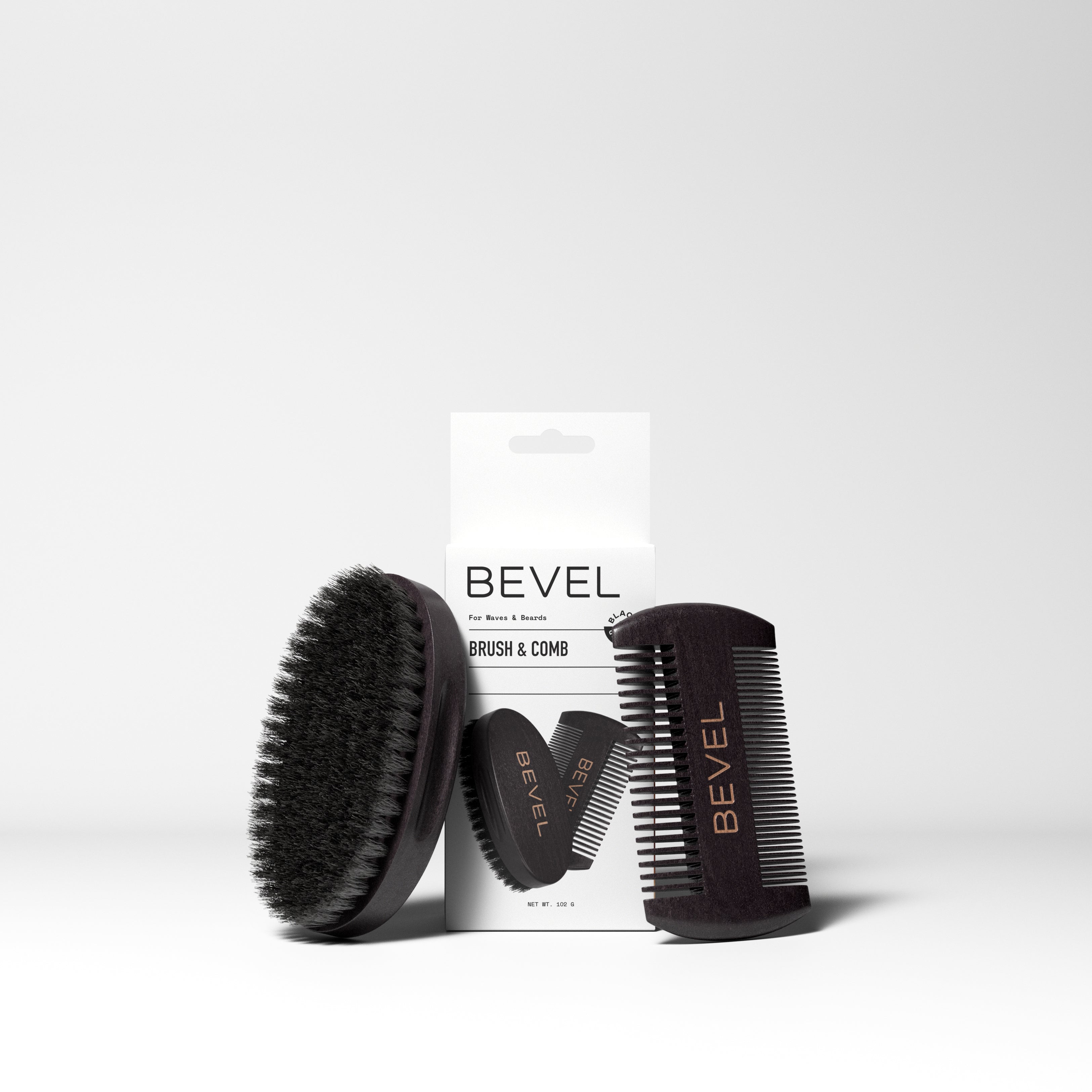A set of grooming tools consisting of a black boar bristle brush and a black pearwood comb, both with the Bevel brand name, displayed in front of their packaging box.