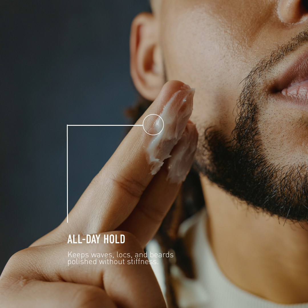 Man applying grooming product to his beard with a dark background