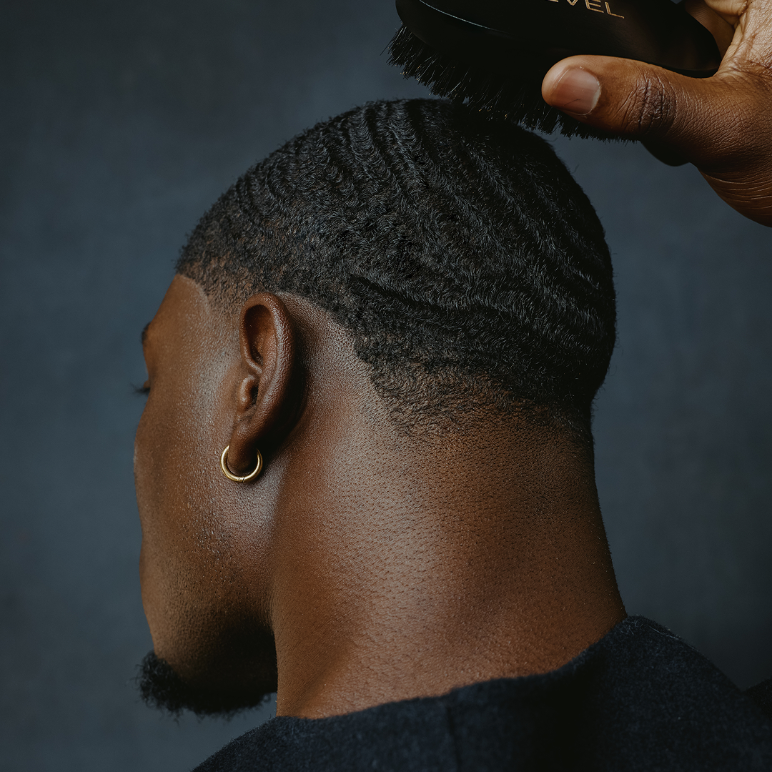 Person getting a haircut with a brush against a dark background