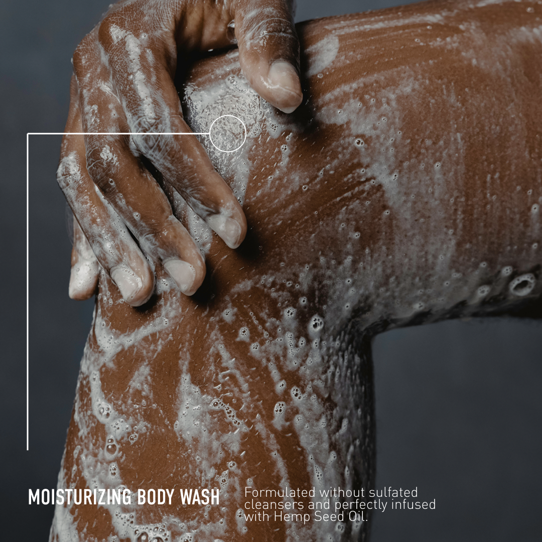 Person scrubbing their arm with a moisturizing body wash against a dark background