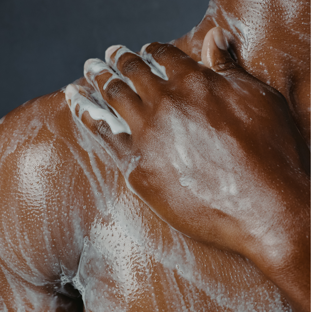 Close-up of a person's hands with soap suds on a dark background