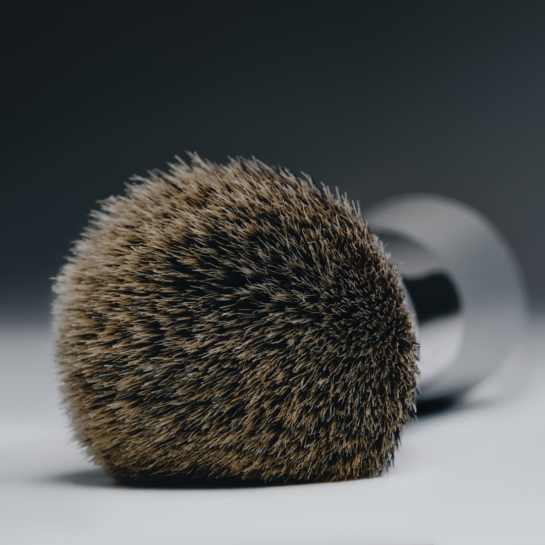 Shaving brush with bristle head and metal handle on a gradient background