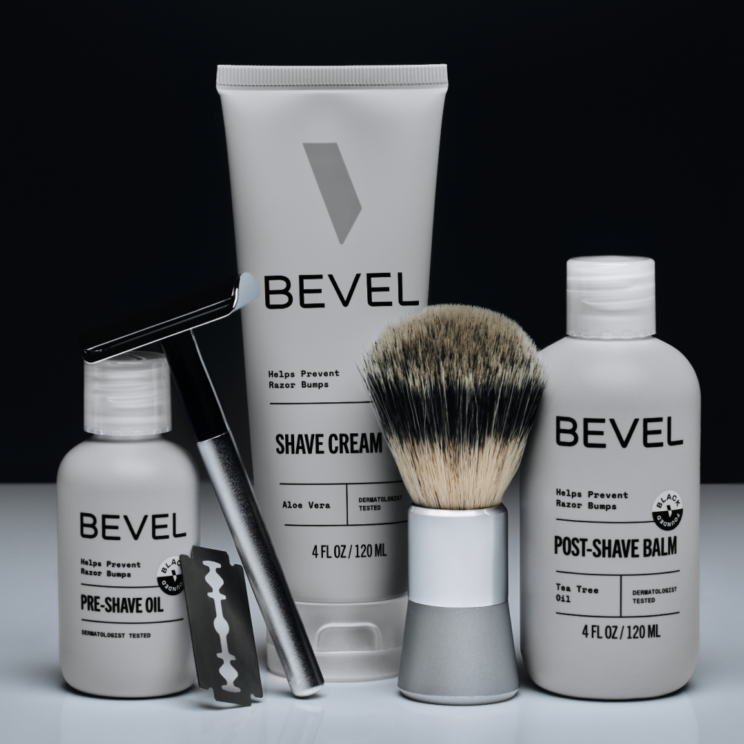 Bevel grooming products including shave cream, pre-shave oil, post-shave balm, and a brush on a black background.
