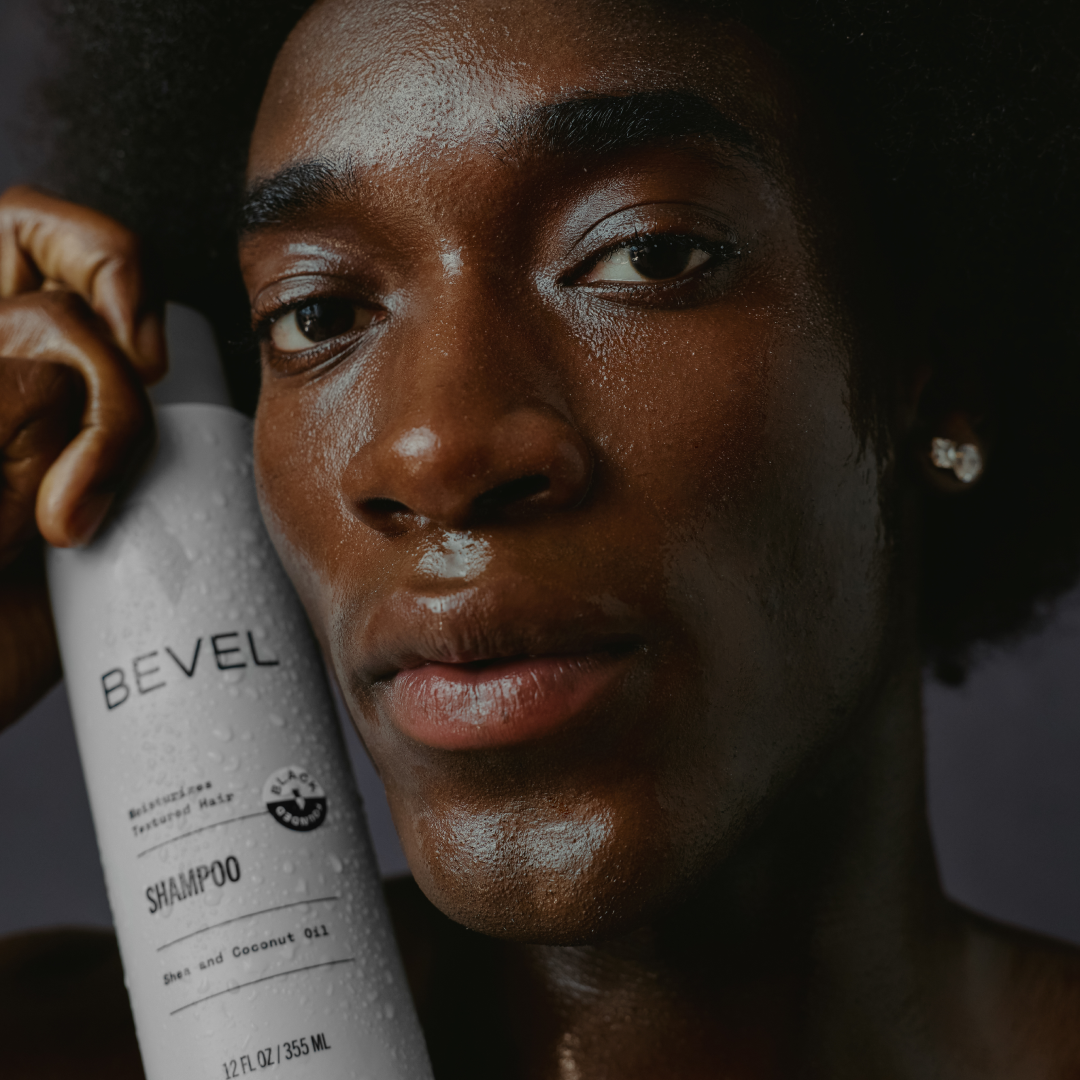 Person holding a BEVEL shampoo bottle with a dark background