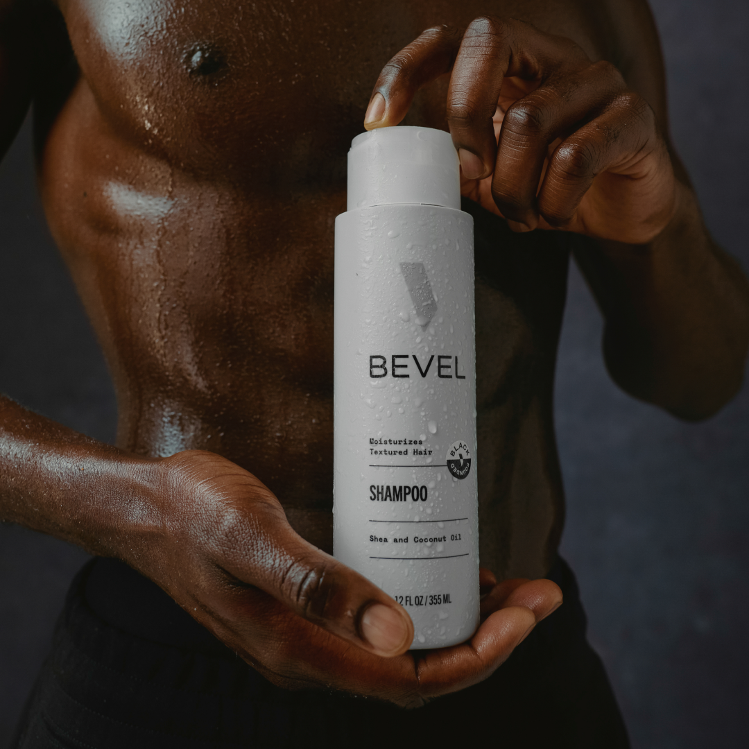Person holding a BEVEL shampoo bottle against a dark background
