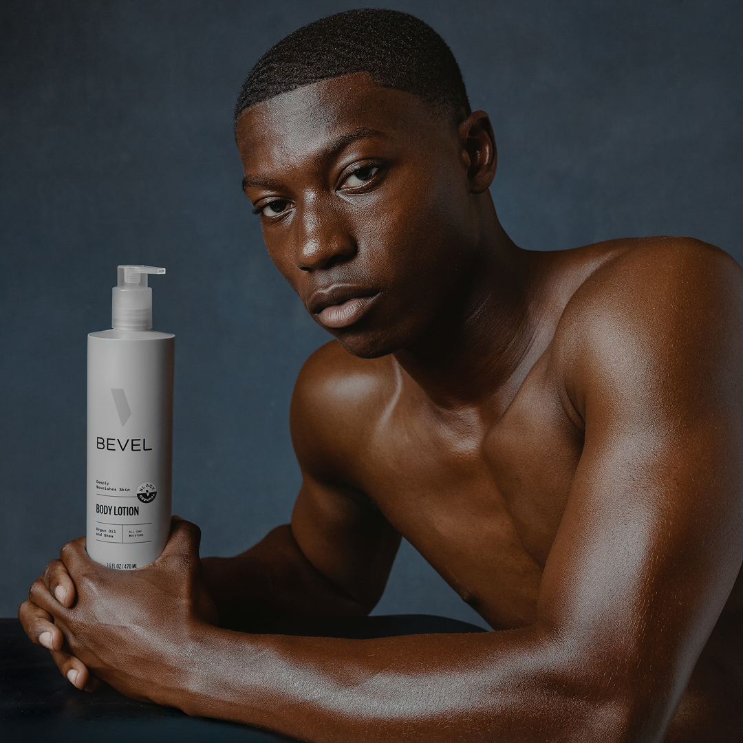 Man holding a BEVEL body lotion bottle against a dark background