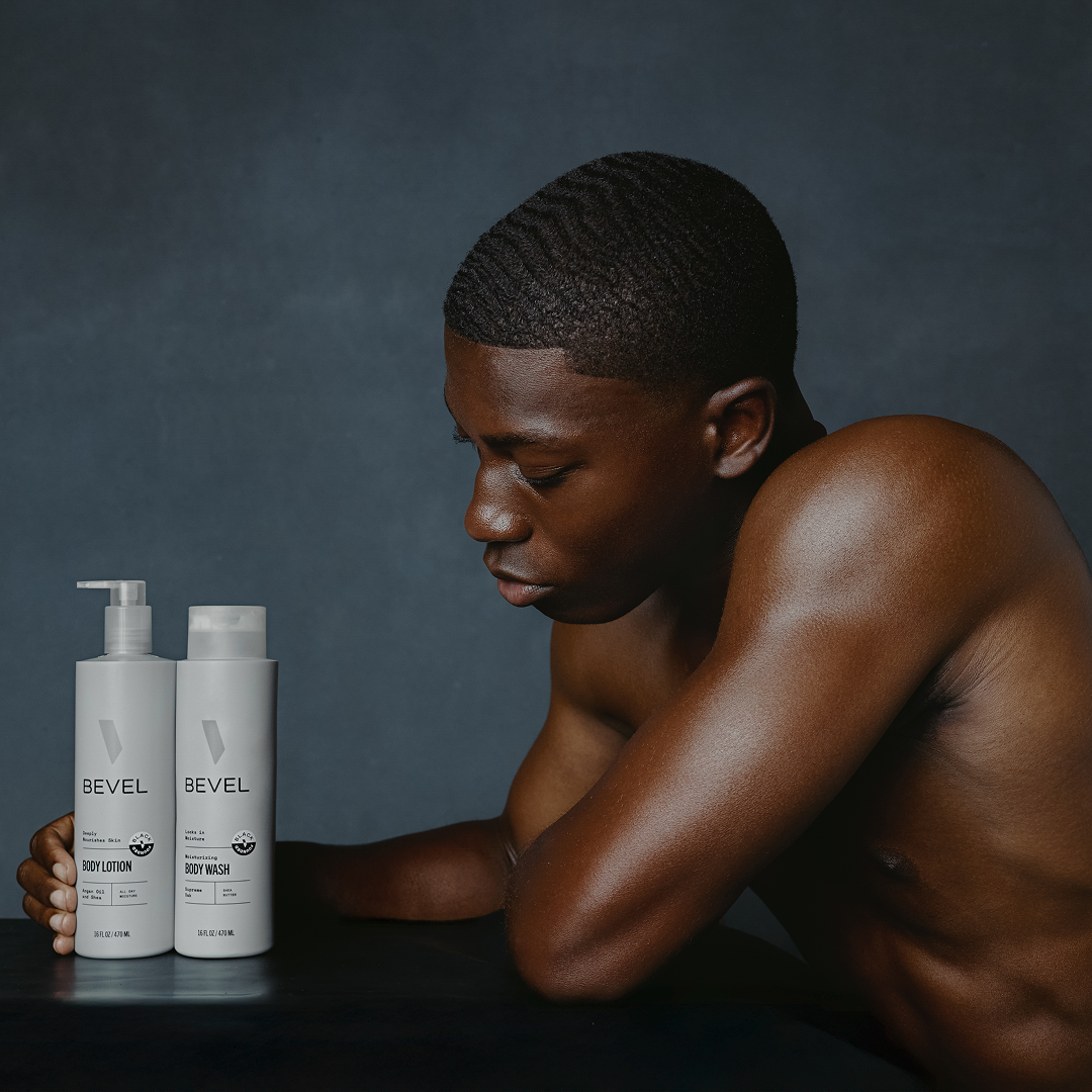 Man sitting with BEVEL body wash bottles on a dark background